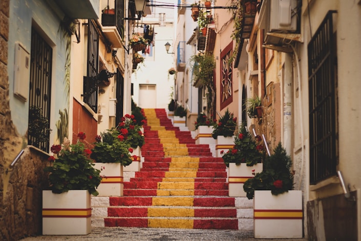 Colorful stairway with red and yellow steps, flanked by flowers, evoking the picturesque scenery 