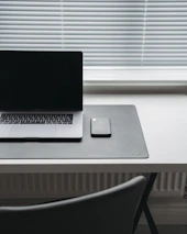 Minimalistic workspace with a smartphone showing an email app, emphasizing professional communication.