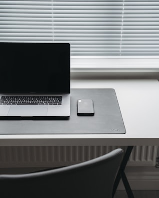 A minimalist workspace showcasing a sleek phone with a screen guard.