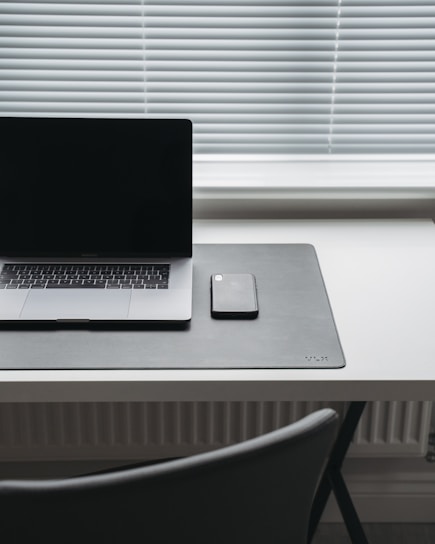 Minimalist workspace featuring a sleek keyboard and smart device on a clean dark desk.