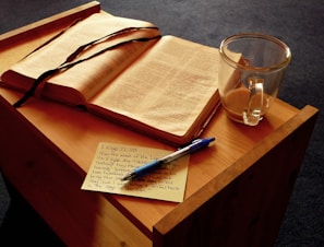 An open book with handwritten notes and a cup of tea on a wooden surface.