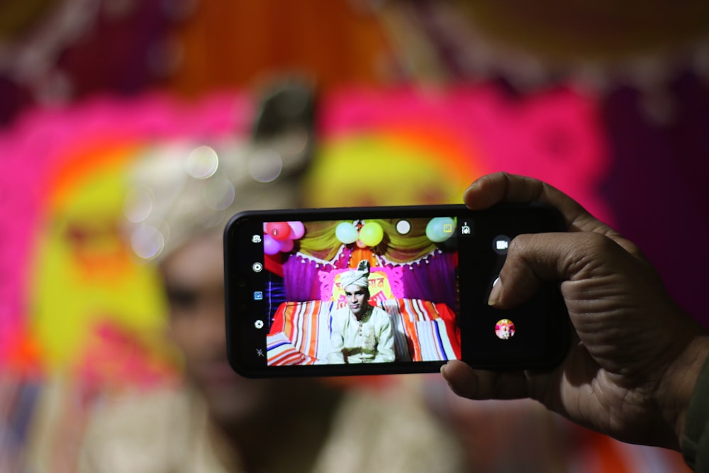 person taking photo of man in traditional shirt with smartphone