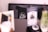 A blurred image of a café setting with a black cushioned bench. In focus is a pillow with white cursive writing that says 'day 2 night'. Nearby objects are out of focus, including a menu or flyer and a bottle with a straw.