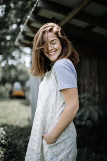 Young woman wearing stylish sunglasses and a watch, smiling outdoors in natural light