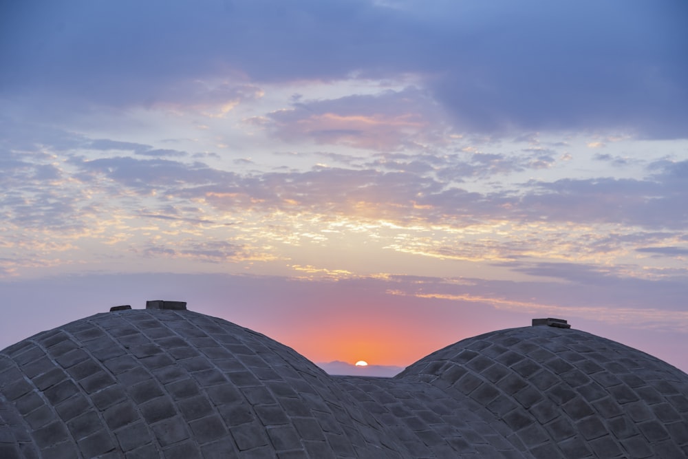 the sun is setting over the domes of a building