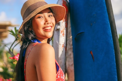 woman wearing sun hat and floral top smiling teams background