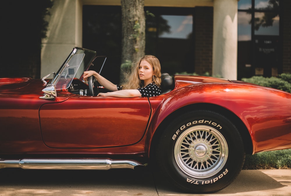 Femme conduisant une voiture décapotable rouge classique