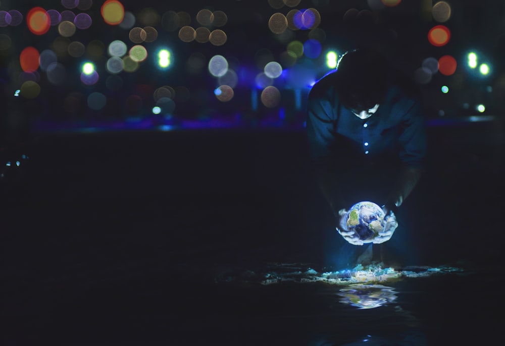 photography of man holding crystal ball during nighttime