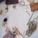 A collection of craft materials including twine, a paintbrush, wooden clothespins, fabric swatches, a pinecone, red beads, and a roll of tape are arranged on a white surface.