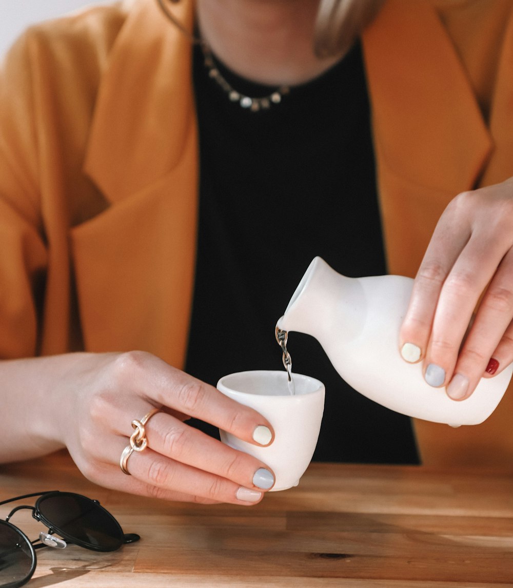 woman pouring water on ceramic shot glass