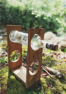 Sunlight filtering through green leaves over a glass bottle of oil.