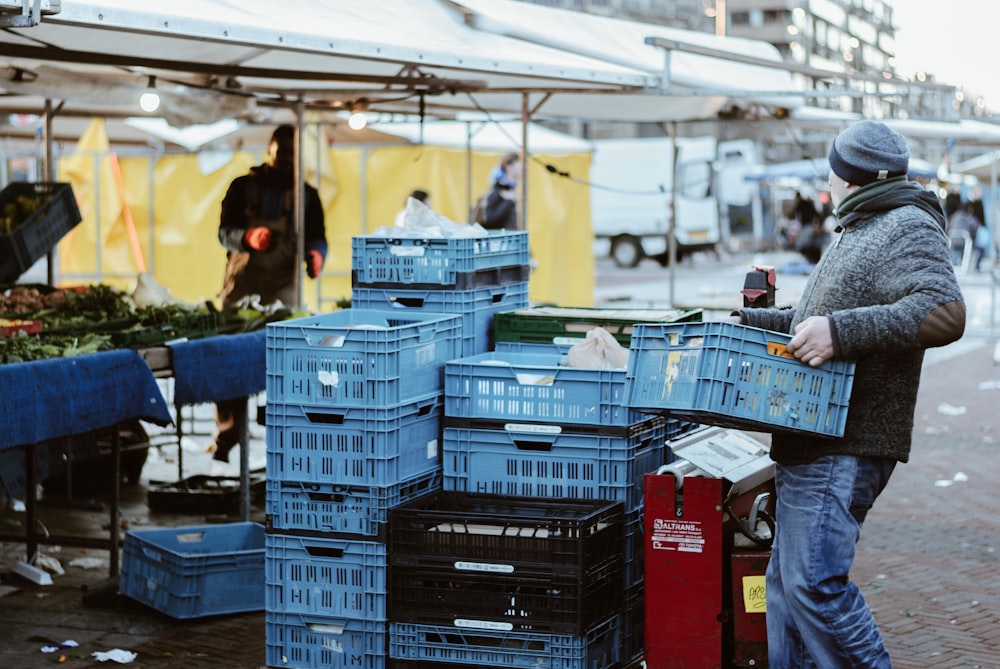 man carrying blue crates
