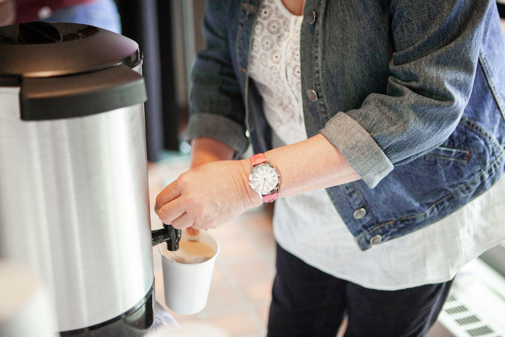 woman filling cup front jar