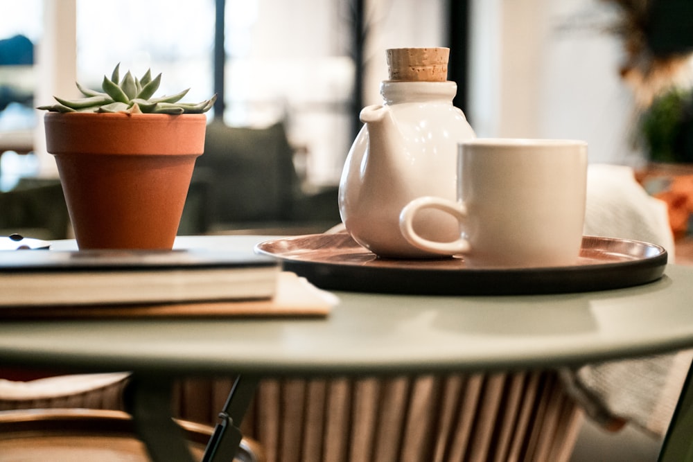 white cup beside teapot on tray