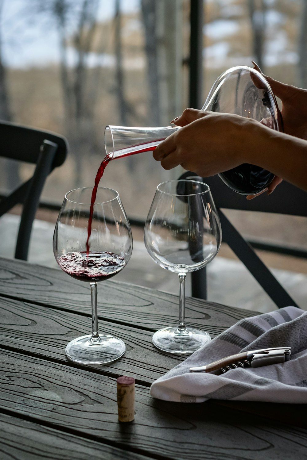 persona che versa il vino dal decanter sul bicchiere di vino