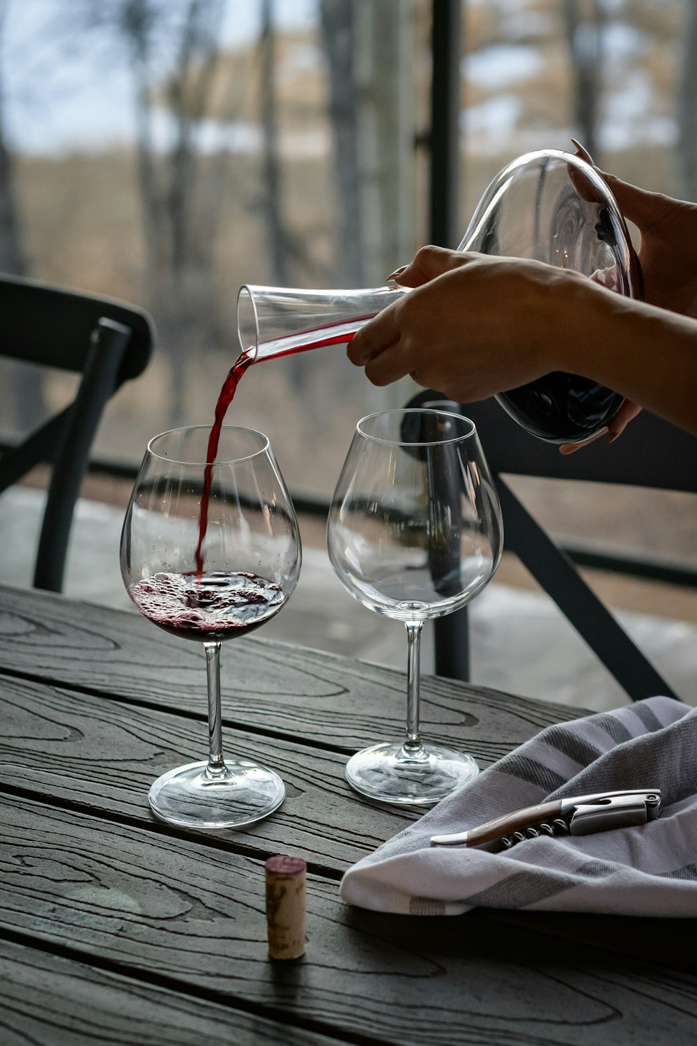 person pouring wine from decanter on wineglass