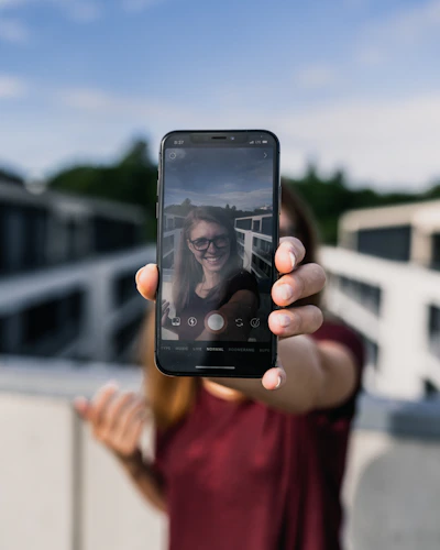 Person wearing stylish smart glasses outdoors, capturing a moment with integrated camera.
