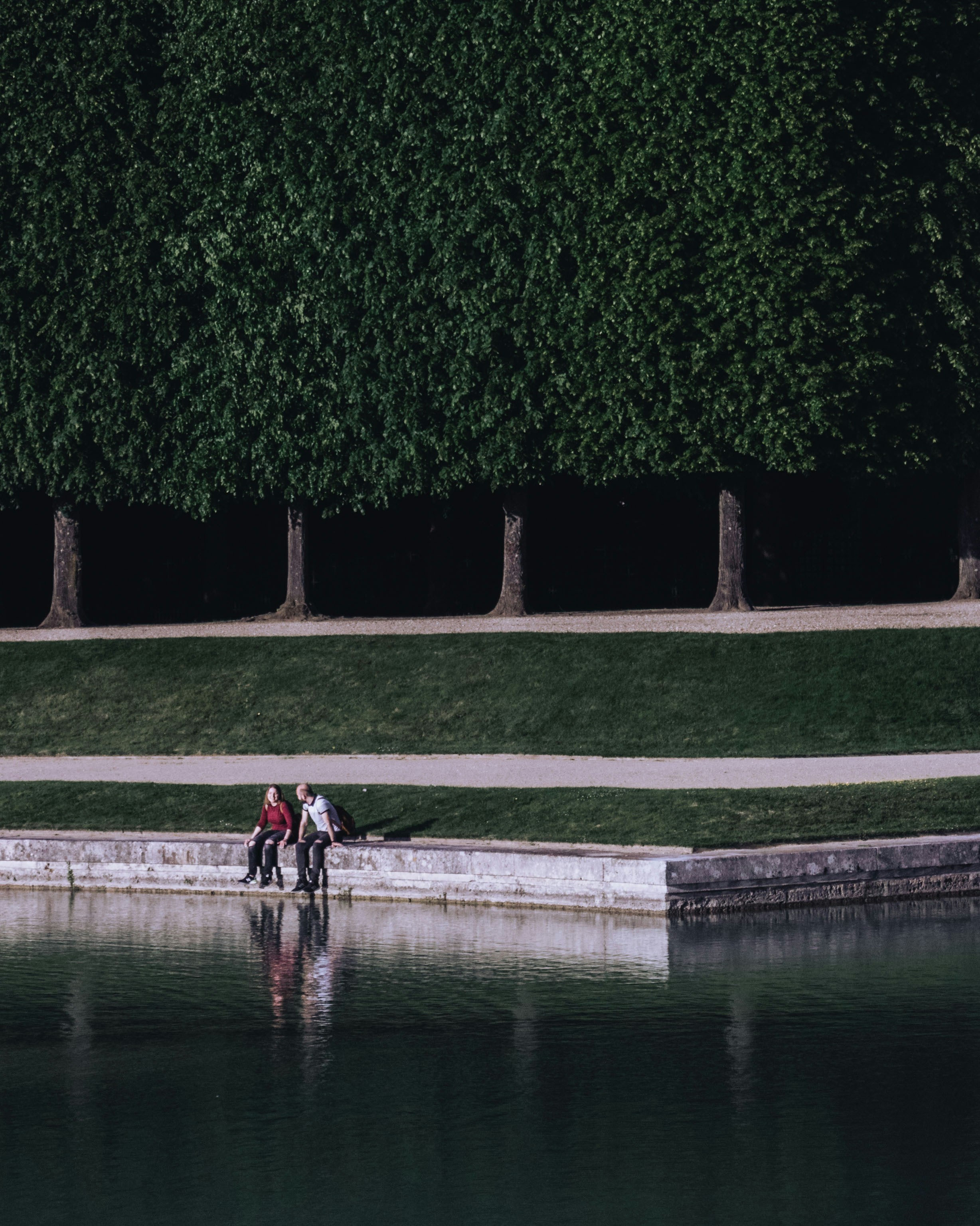 man and woman sitting on pond lake
