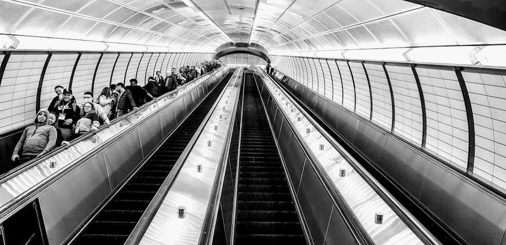 grayscale photo of people on escalator