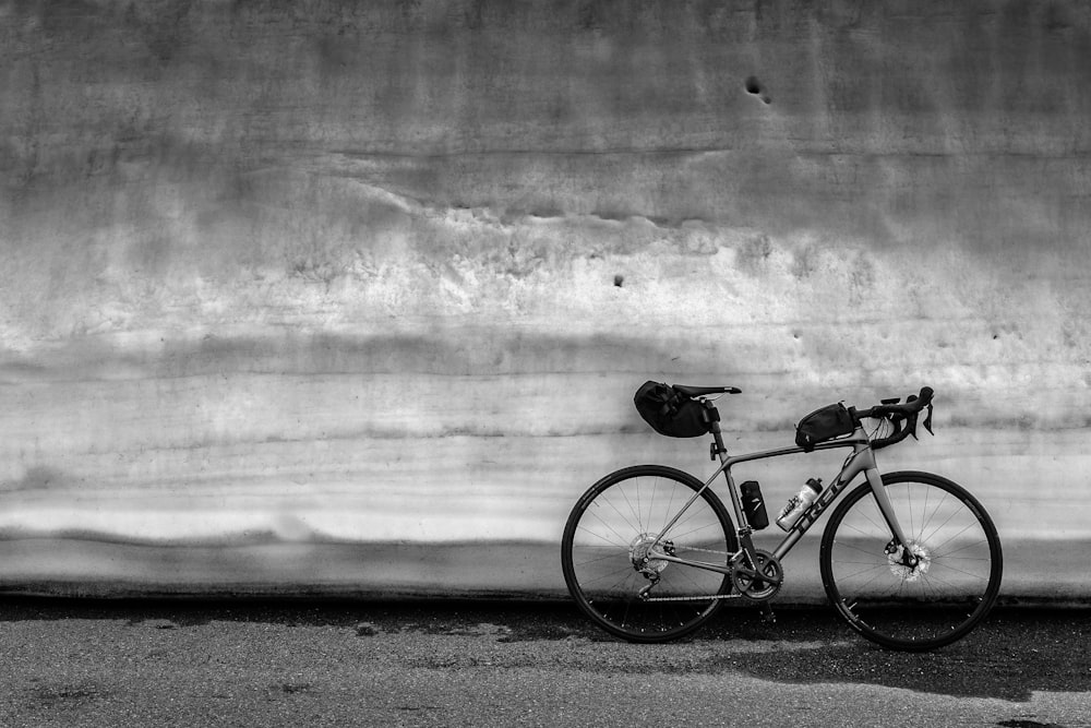 gray bicycle parked beside wall