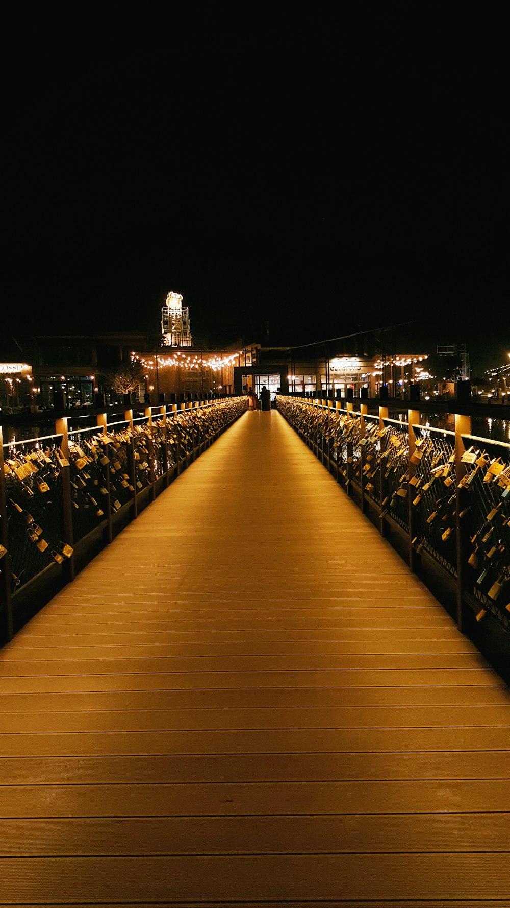 a long wooden walkway leading to a building at night