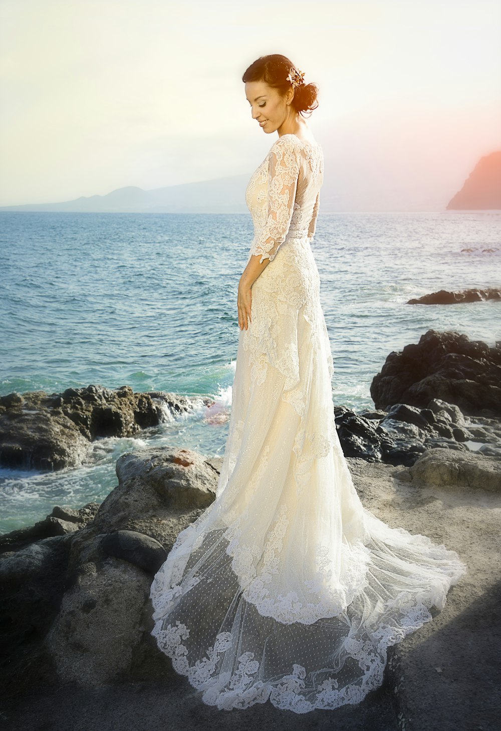 woman wearing white gown standing on rocks across body of water