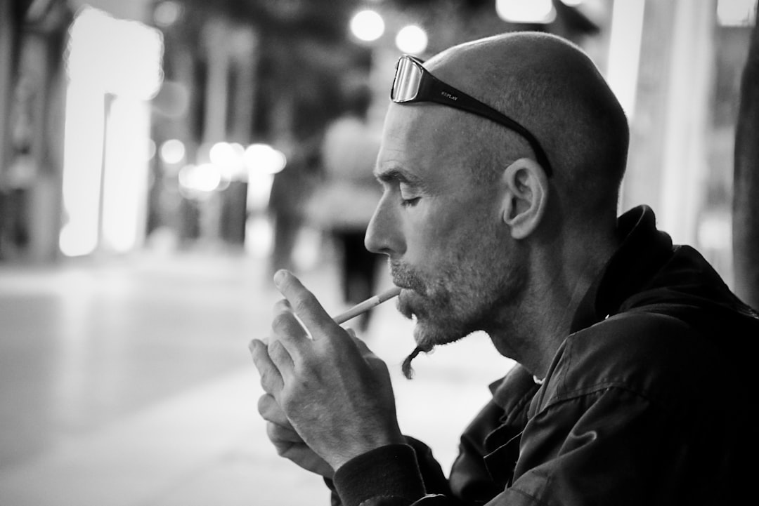 grayscale photo of man lighting cigarette