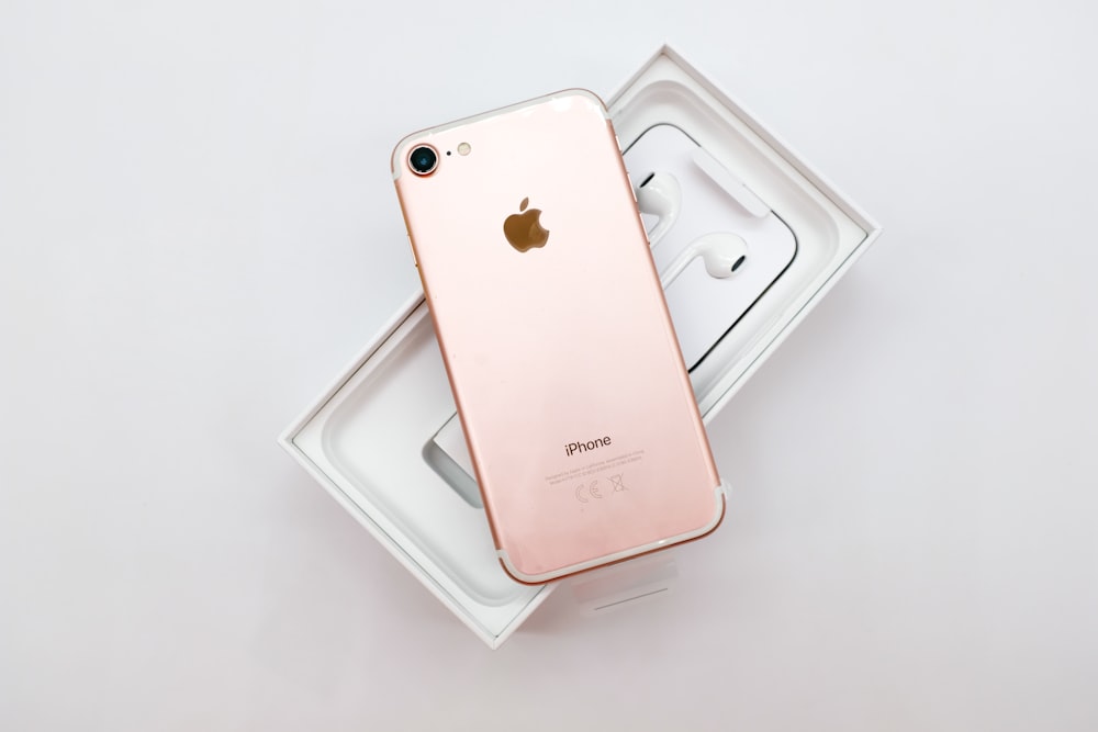 rose gold iPhone 7 with AirPods and box on white surface