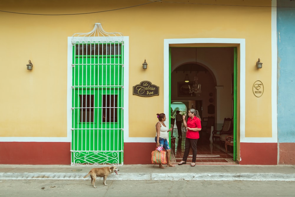 two women standing beside the doorway near dog