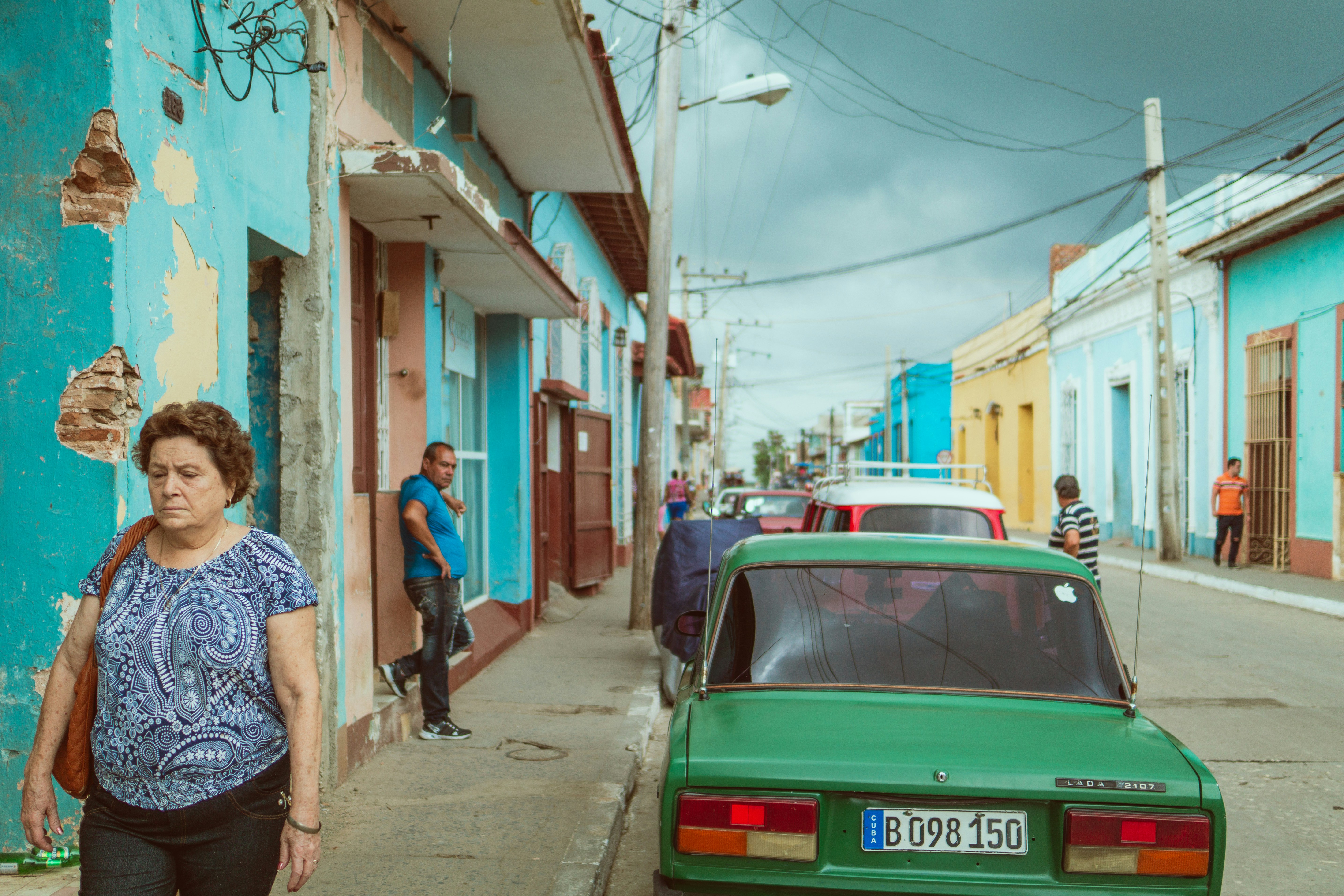 woman walking beside green vehicle during daytime