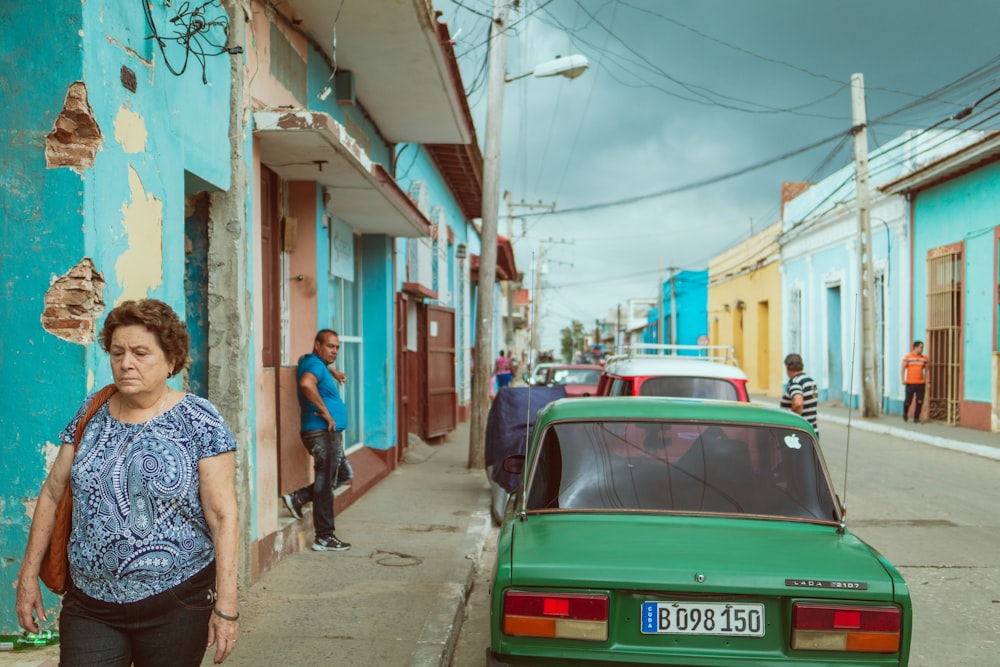 woman walking beside green vehicle during daytime