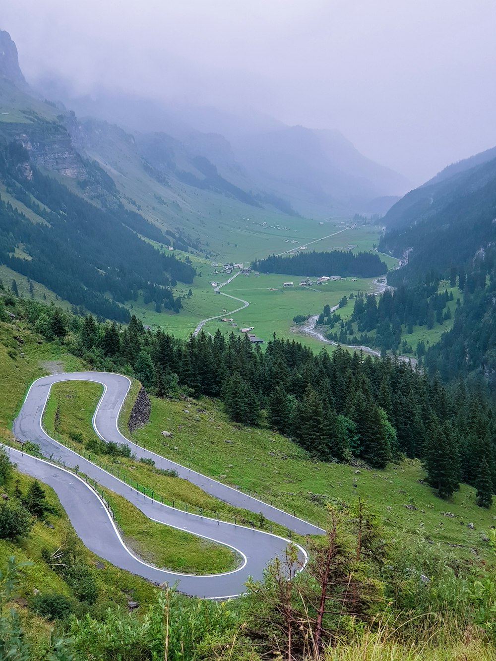 spiral road near green field and mountain view