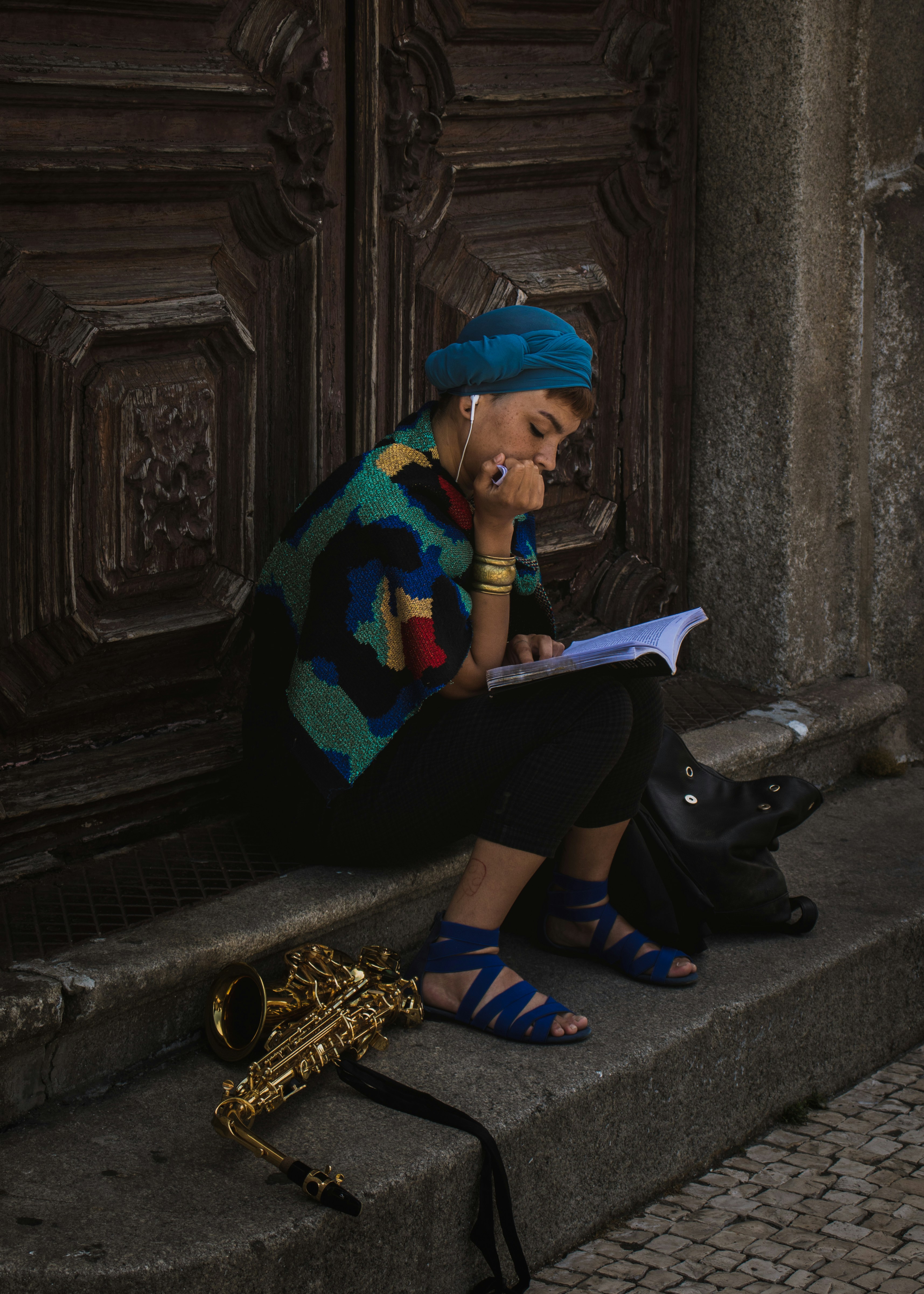 woman sitting in front of wooden doors listening to songs and romanticizing her life