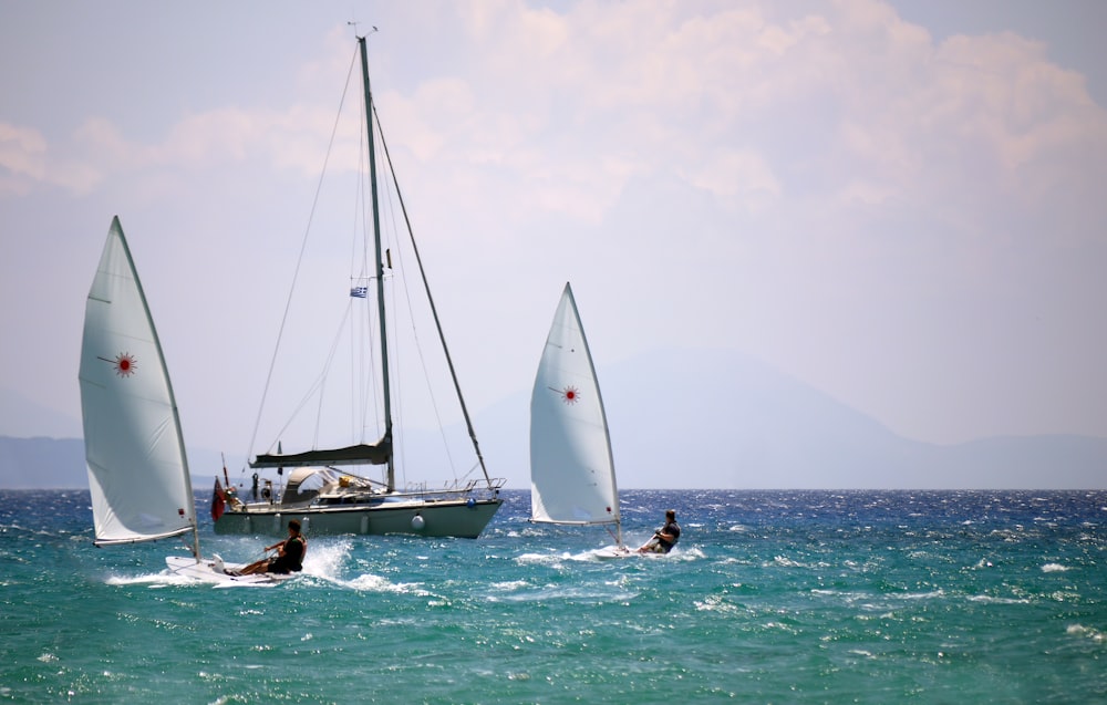 two men windsurfing past anchored yacht at sea