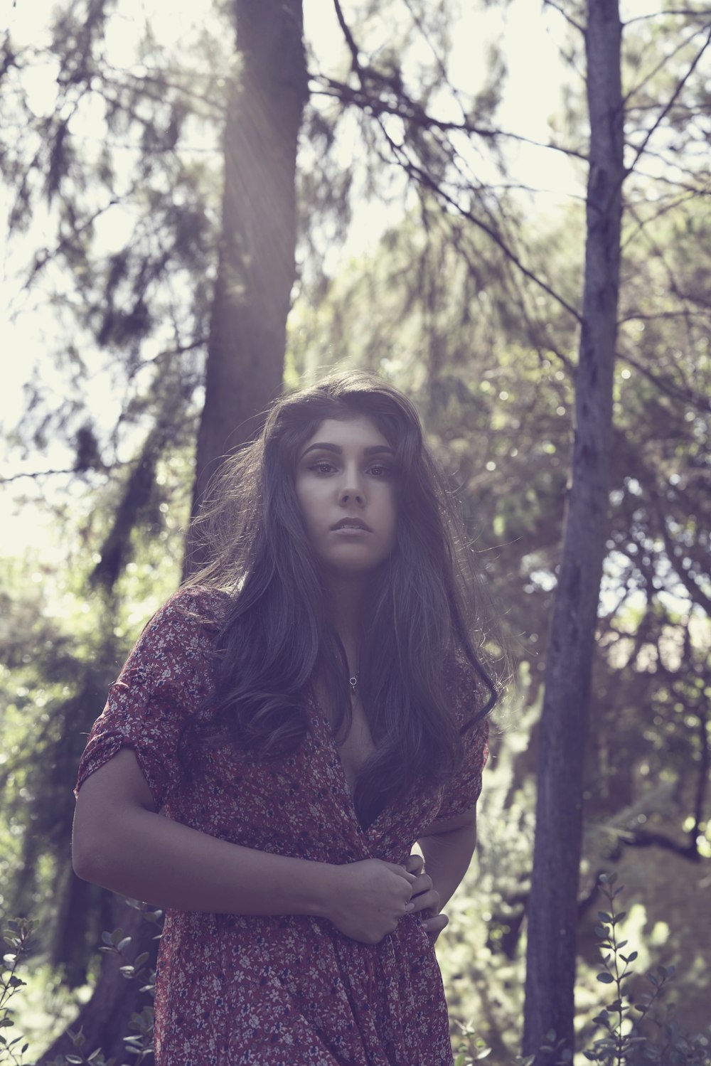 Femme en robe marron et beige debout sous les arbres