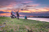 A shiny red Indian scooty parked near the steps of the Ganges at sunrise