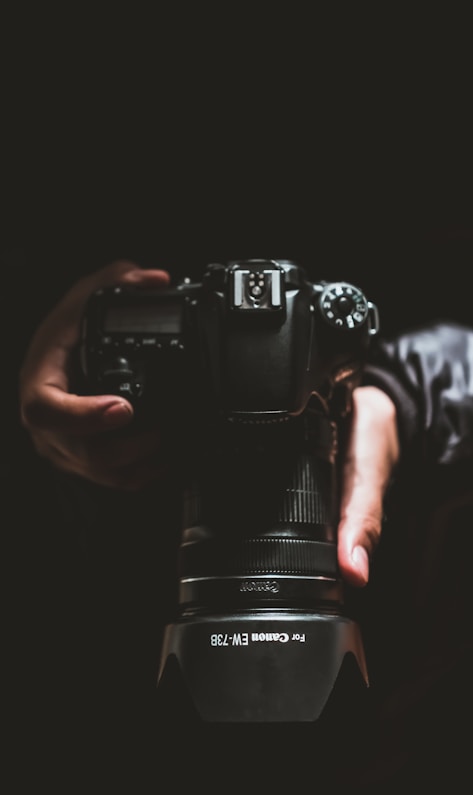 person holding black Canon DSLR camera