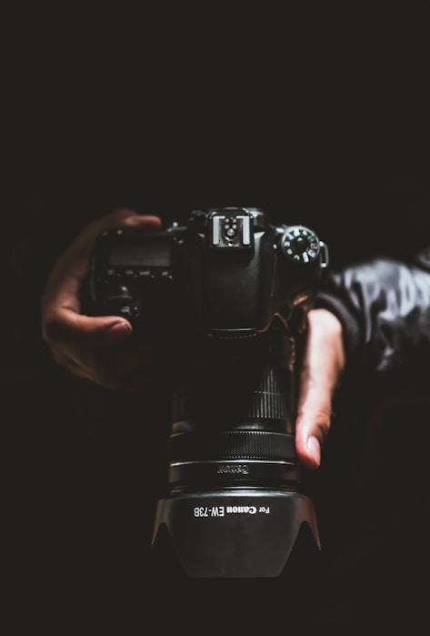 person holding black Canon DSLR camera