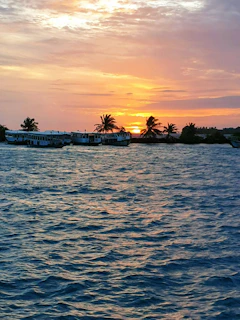 A vibrant sunset over the calm waters surrounding Pulau Peling with boats anchored nearby