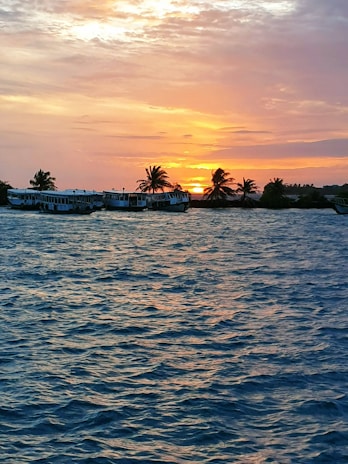 A vibrant sunset over the turquoise waters of Islas del Rosario with small boats anchored nearby.