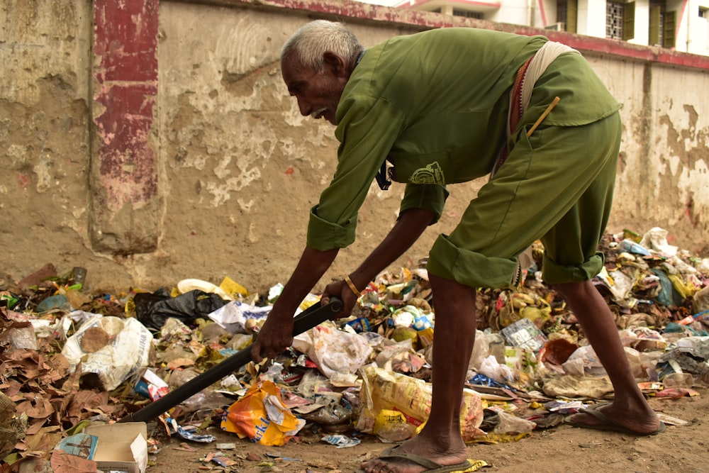 man holding branch searching at the dump