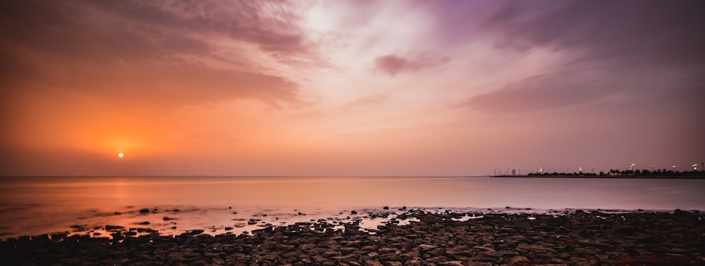 brown stone near seashore during sunset