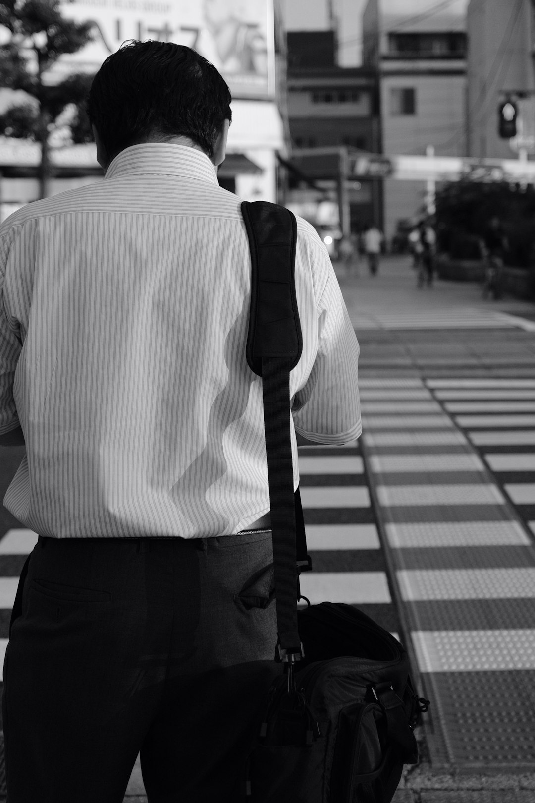 grayscale photography of man carrying bag