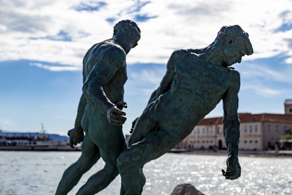 two men statue near body of water during daytime