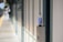 A plastic bottle with a blue label and cap is placed on top of an emergency call box at a train or subway platform. The platform is mostly empty, with blurred background showing part of the tracks and another person in the distance.