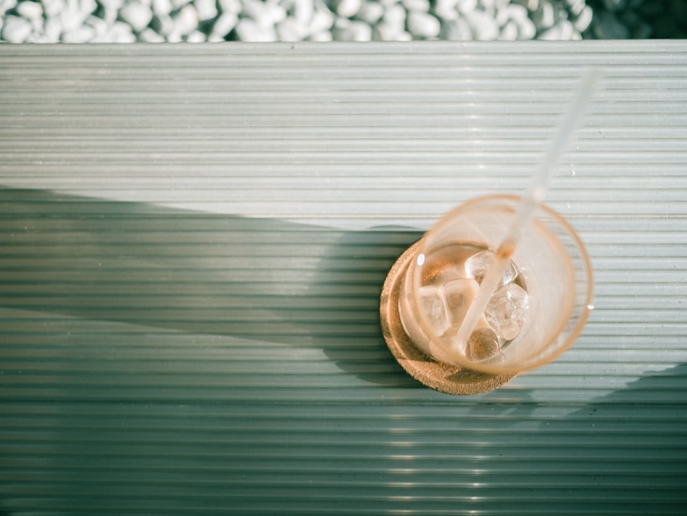 fotografia plana de vidro com cubos de gelo e palha