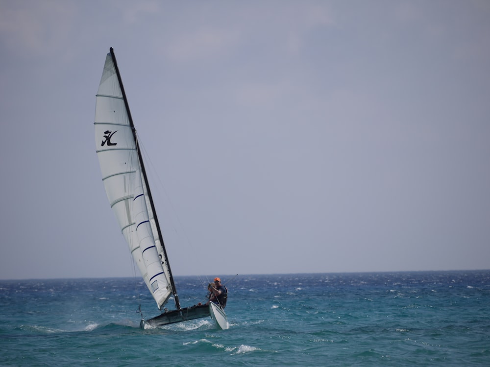 two men riding a sailboat in the sea