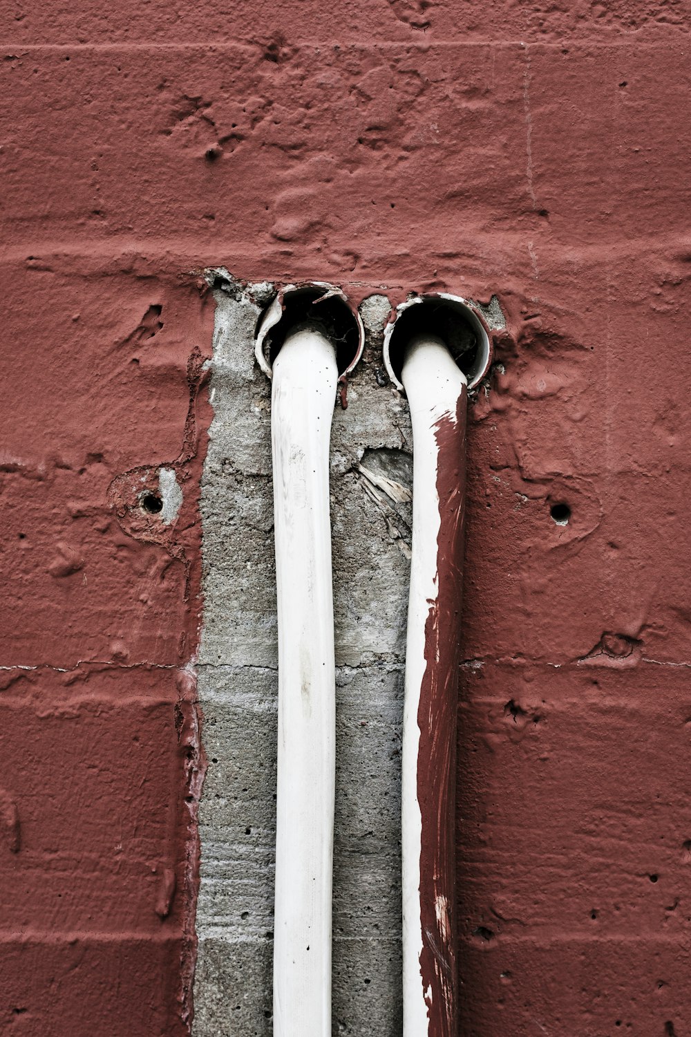 two white pipes sticking out of a brick wall