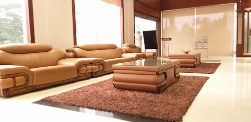 A spacious luxury home lounge featuring a designer console and statement furniture pieces in dark brown and gold tones.