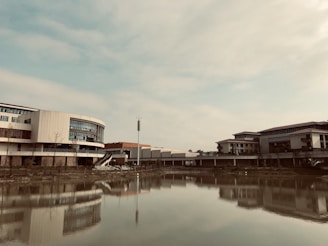 A serene landscape blending modern eco-friendly buildings with lush greenery under a clear blue sky.